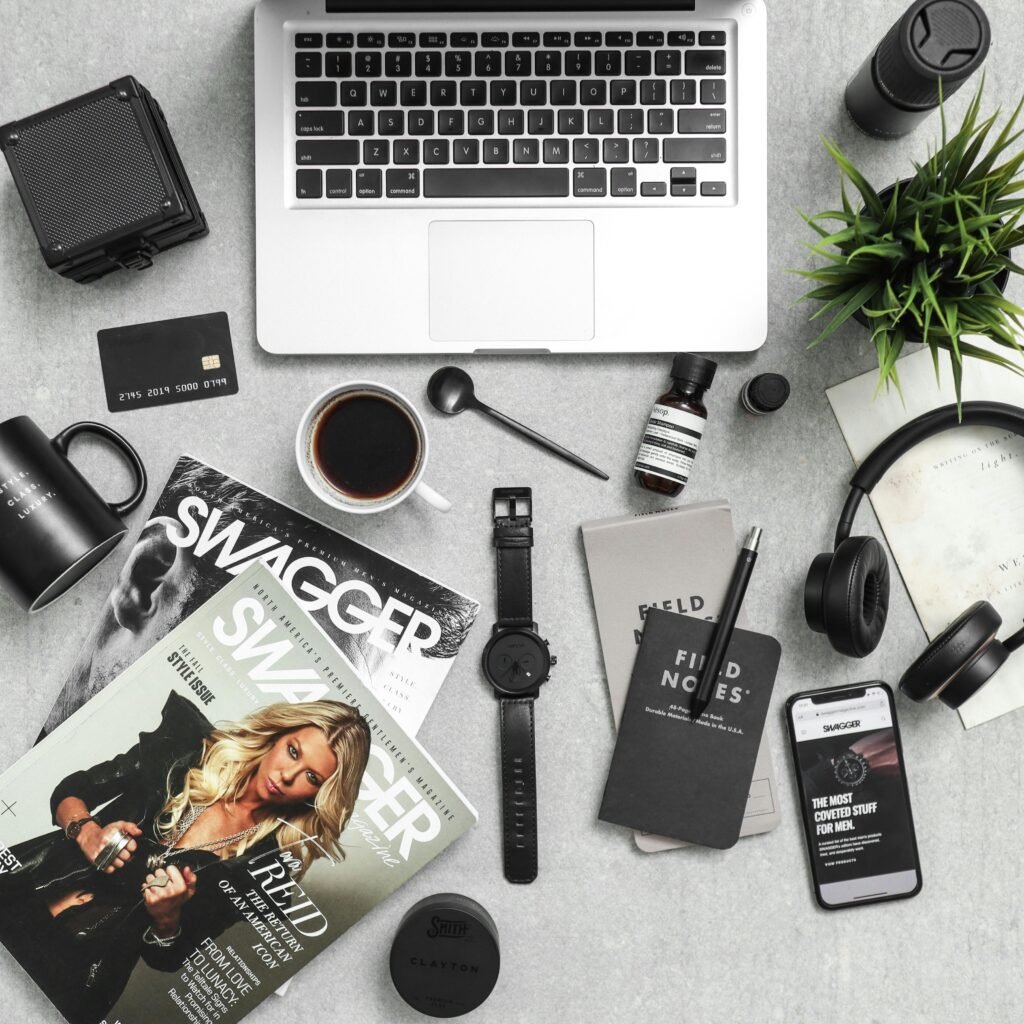 Flat lay of a stylish workspace with laptop, phone, coffee, and tech accessories.